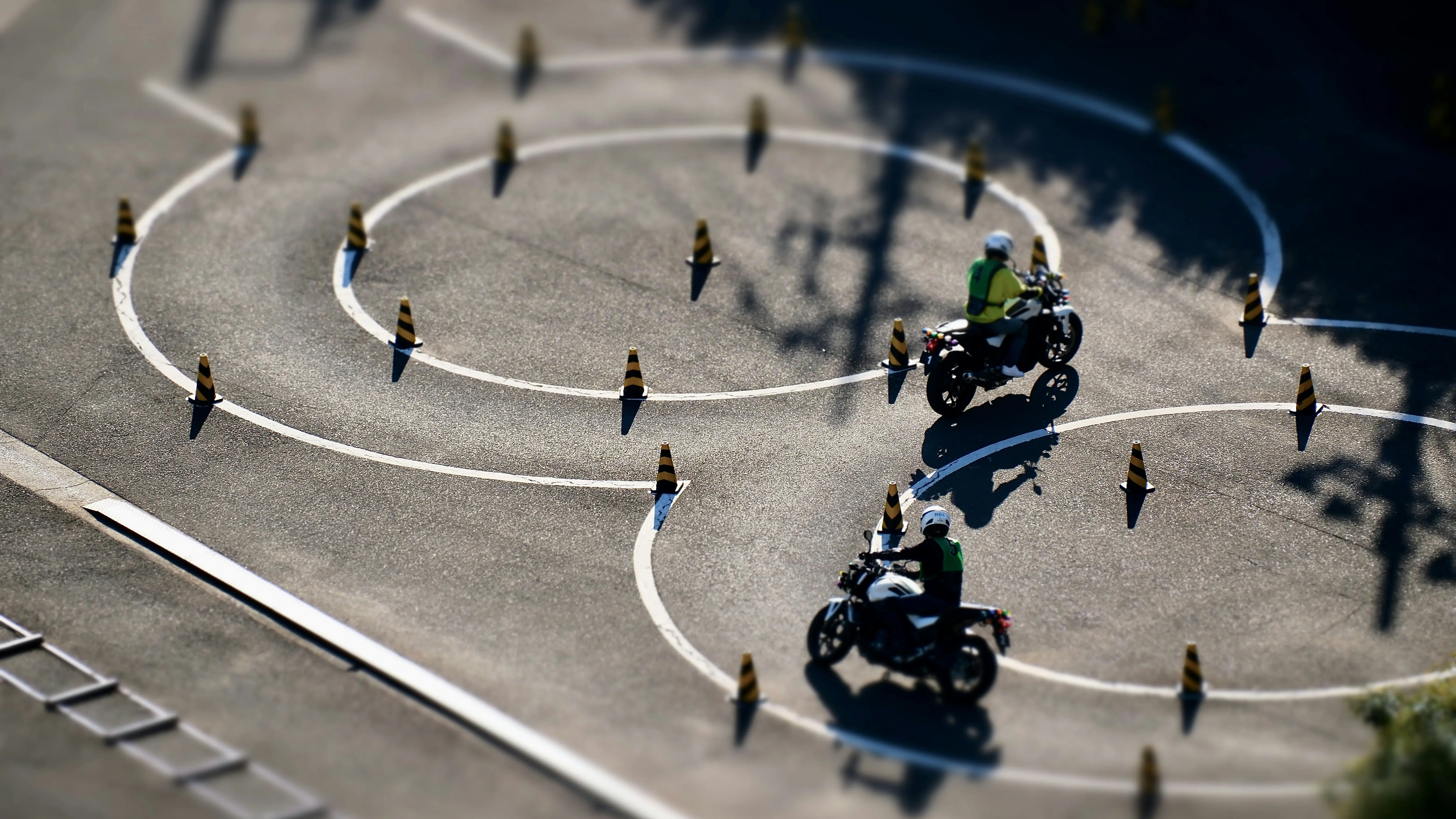 Két motoros gyakorol a tanpályán, bóják között, felülnézetből